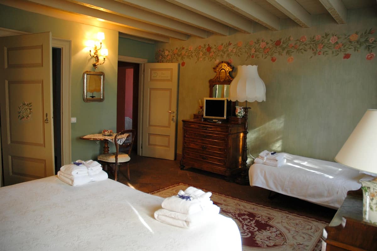 A hotel room with two beds, a television, a dresser, and a small table with a chair.
