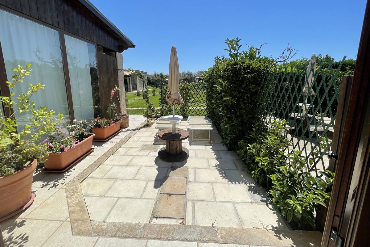 A patio area with potted plants, a table, and a chair.