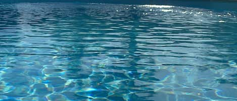 Una piscina al aire libre de temporada, sombrillas