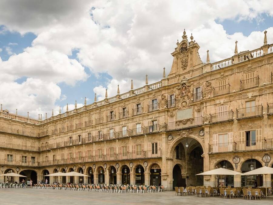 Um edifício histórico com um pátio, apresentando varandas ornamentadas e um arco central.