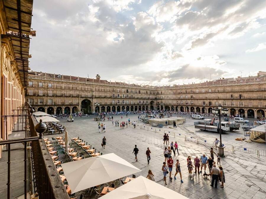 Un amplio patio con varios niveles de arcos, zonas de estar al aire libre y una fuente central.