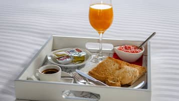 A tray with toast, butter, jam, a glass of orange juice, and a cup of coffee.