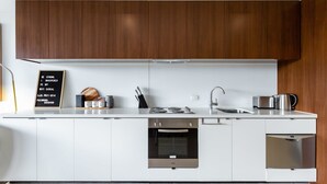 Une cuisine moderne avec des meubles blancs, un four encastré, un lave-vaisselle et une machine à café.