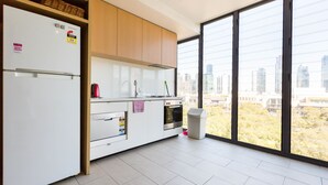 A modern kitchen with a large window, a refrigerator, oven, and a sink. - Leila, 1BDR Melbourne Apartment (Melbourne)