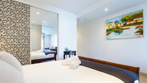 A hotel room with a bed, a painting on the wall, and a mirror reflecting the room. - Leila, 1BDR Melbourne Apartment (Melbourne)