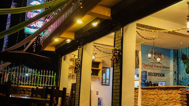 A hotel reception area with a stone wall, a reception desk, and a sign that reads "Quotel Guest House." - Quetzel Guest House (Pokhara)