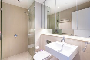 Un baño moderno con cabina de ducha de vidrio, un lavabo blanco y un espejo grande.