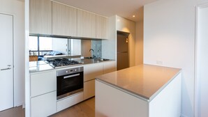 A modern kitchen with white cabinetry, stainless steel appliances, and a large island. - Sabrina, 2BDR Docklands Apartment (Docklands)