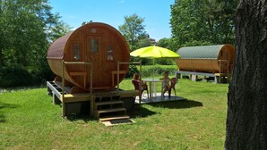 A wooden cabin with a ramp and a table with chairs under a yellow umbrella. - Camping Le Parc les Atypiques (Availles-Limouzine)