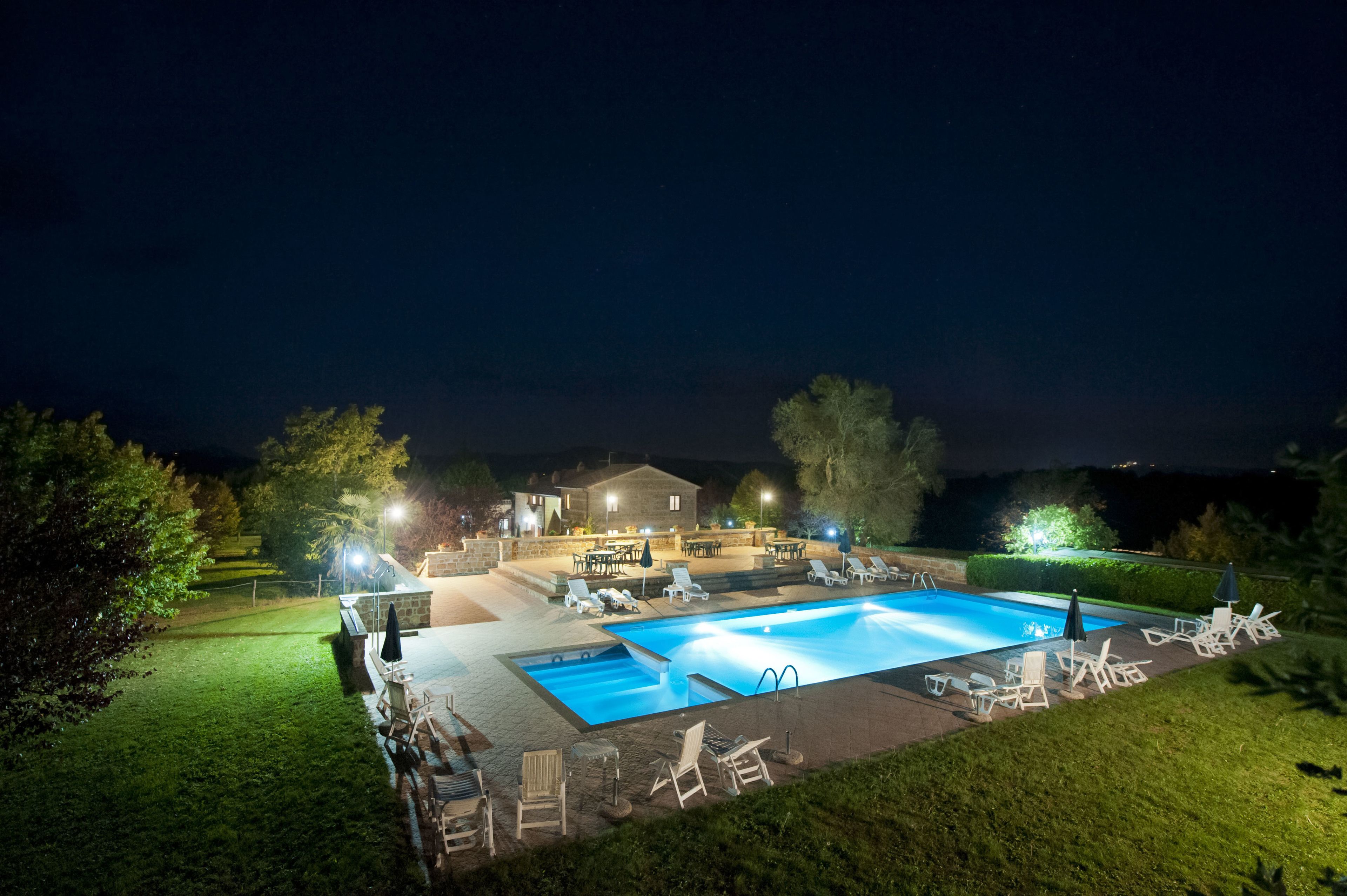 Una piscina con sillones de descanso y una casa al fondo.