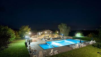 Una piscina con sillones de descanso y una casa al fondo.