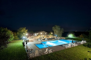A swimming pool with lounge chairs and a house in the background.