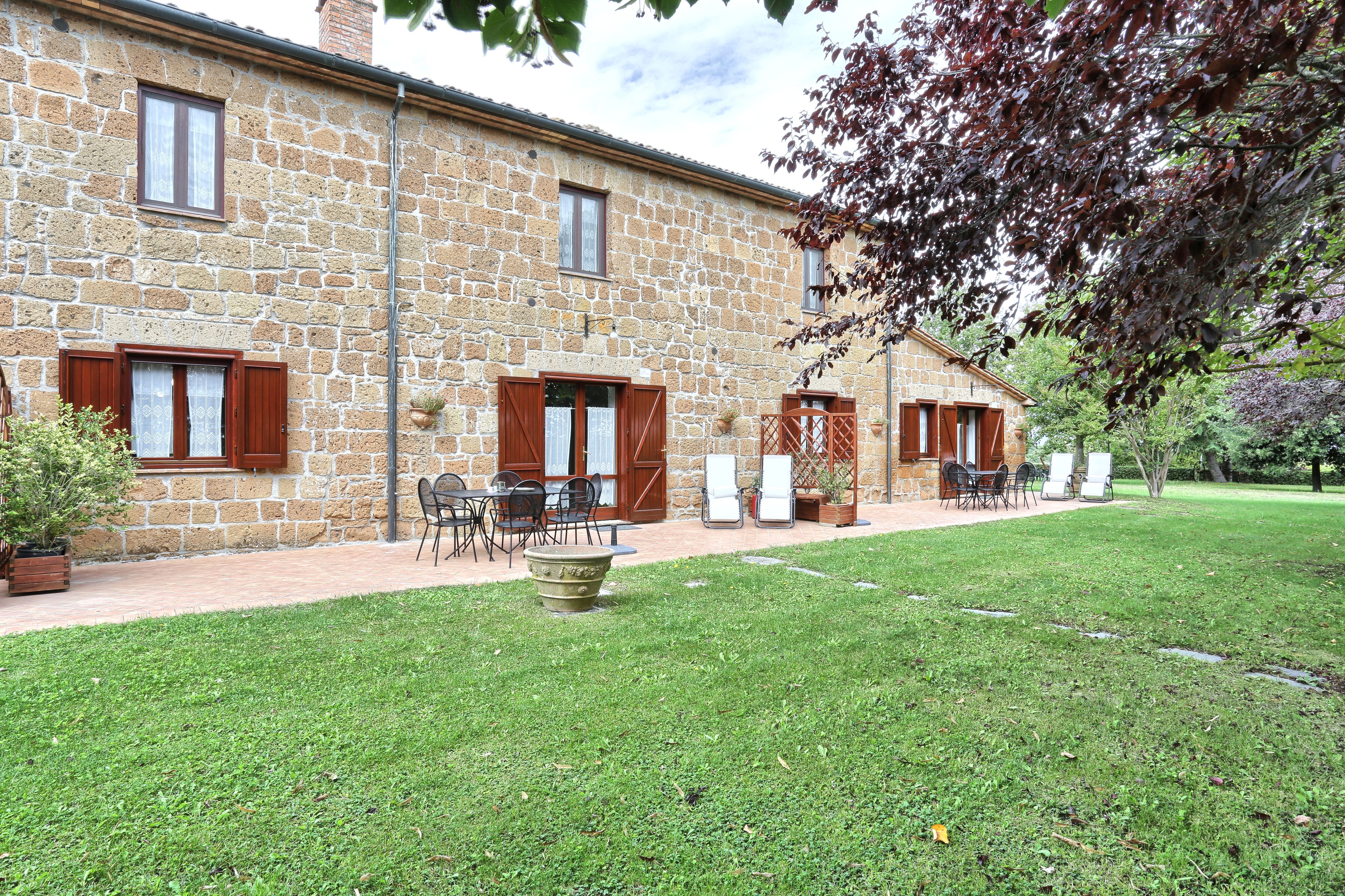 A stone building with a patio area, outdoor seating, and a well-maintained lawn.