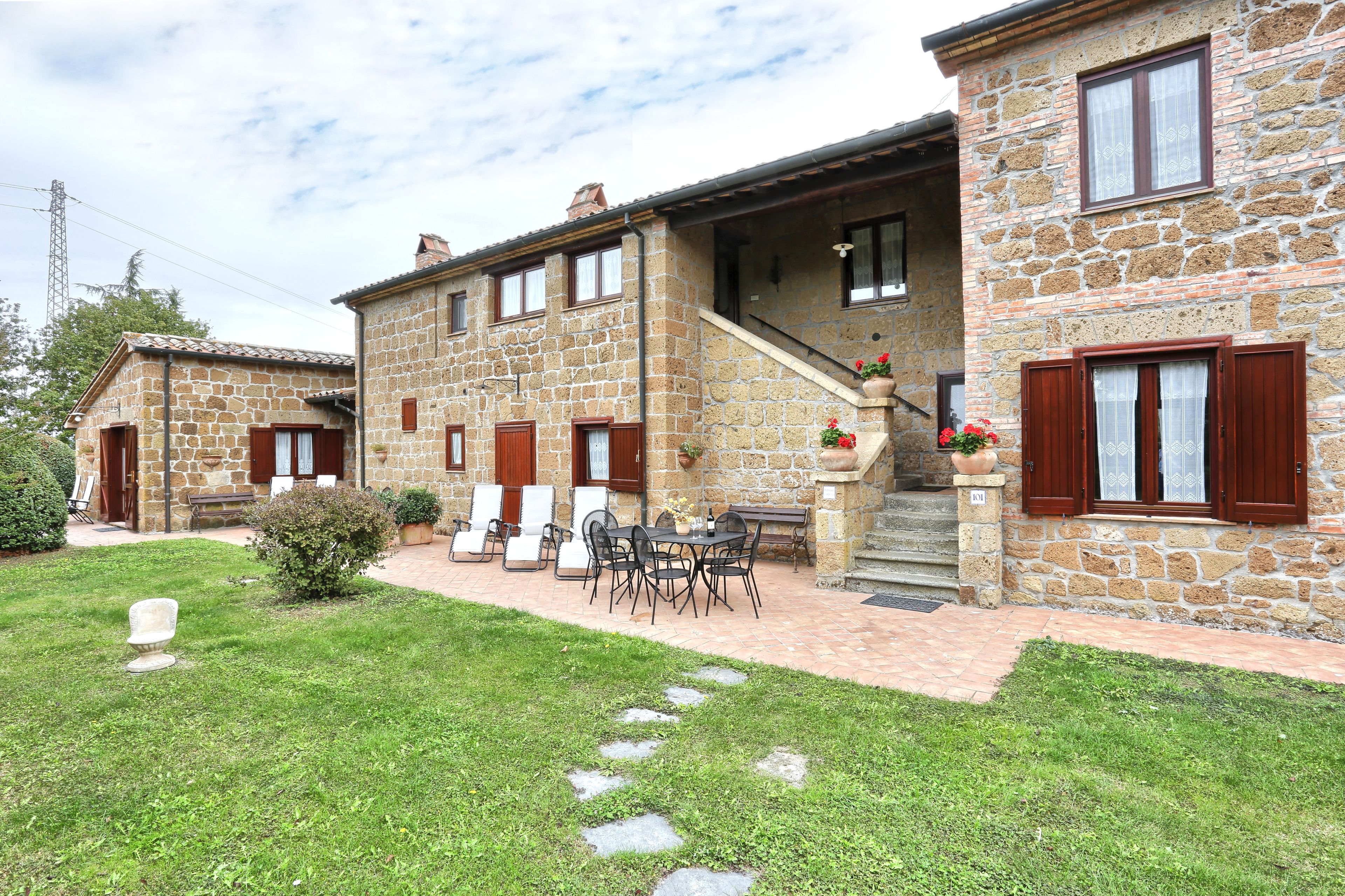 A stone building with a patio area featuring outdoor furniture and a staircase.