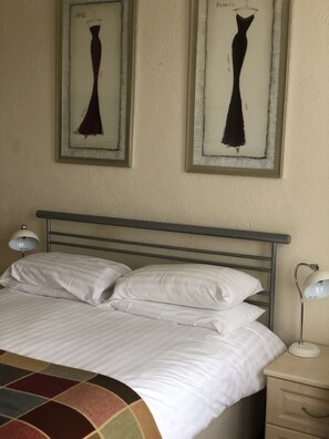 A bed with white linens, a metal headboard, and two bedside lamps. - The Hunt Lodge (Leighton Buzzard)