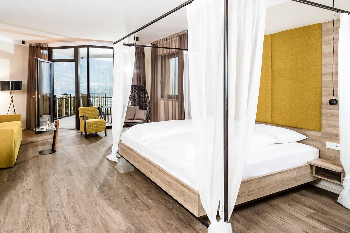 A hotel room with a bed, a desk, a chair, a balcony with a view, and a TV.