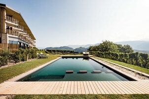 Una piscina al aire libre, sombrillas, sillones reclinables de piscina