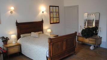 Un dormitorio con cama de madera, lámparas de noche, cómoda y espejo.