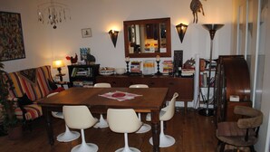 Un comedor con una mesa de madera, sillas blancas y un sofá.