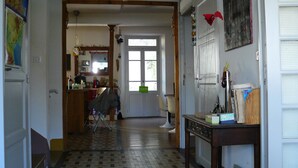 Un pasillo con suelo de baldosas, una puerta de madera y una mesa con varios objetos encima.