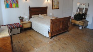 Un dormitorio tradicional con cama de madera, mesitas de noche, un banco y un aparador.