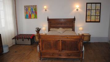 A wooden bed with a headboard, two bedside lamps, and a colorful painting on the wall.