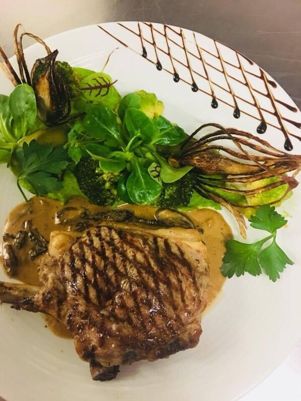 Um prato com bife grelhado, legumes verdes e um molho.