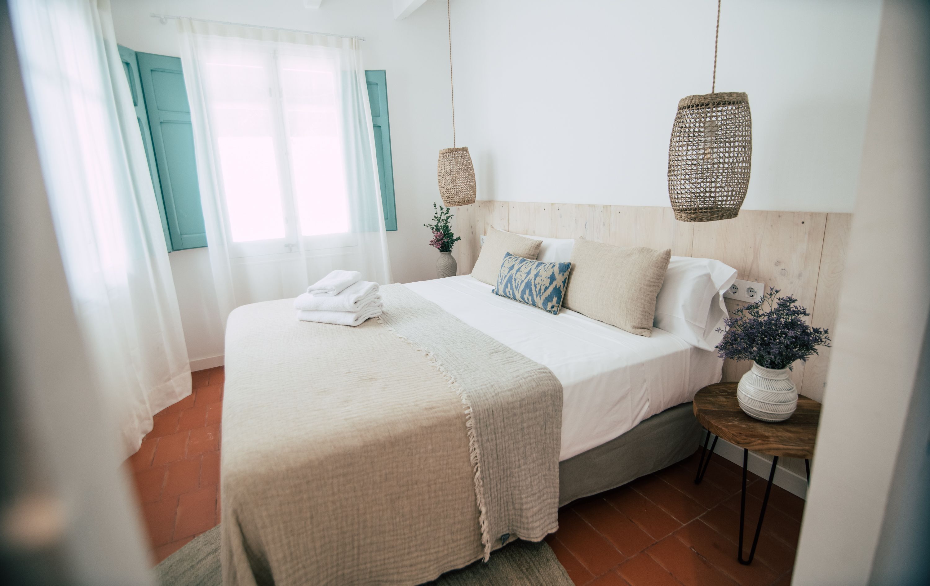 Une chambre bien rangée, avec un lit, des tables de chevet et une fenêtre avec des rideaux.