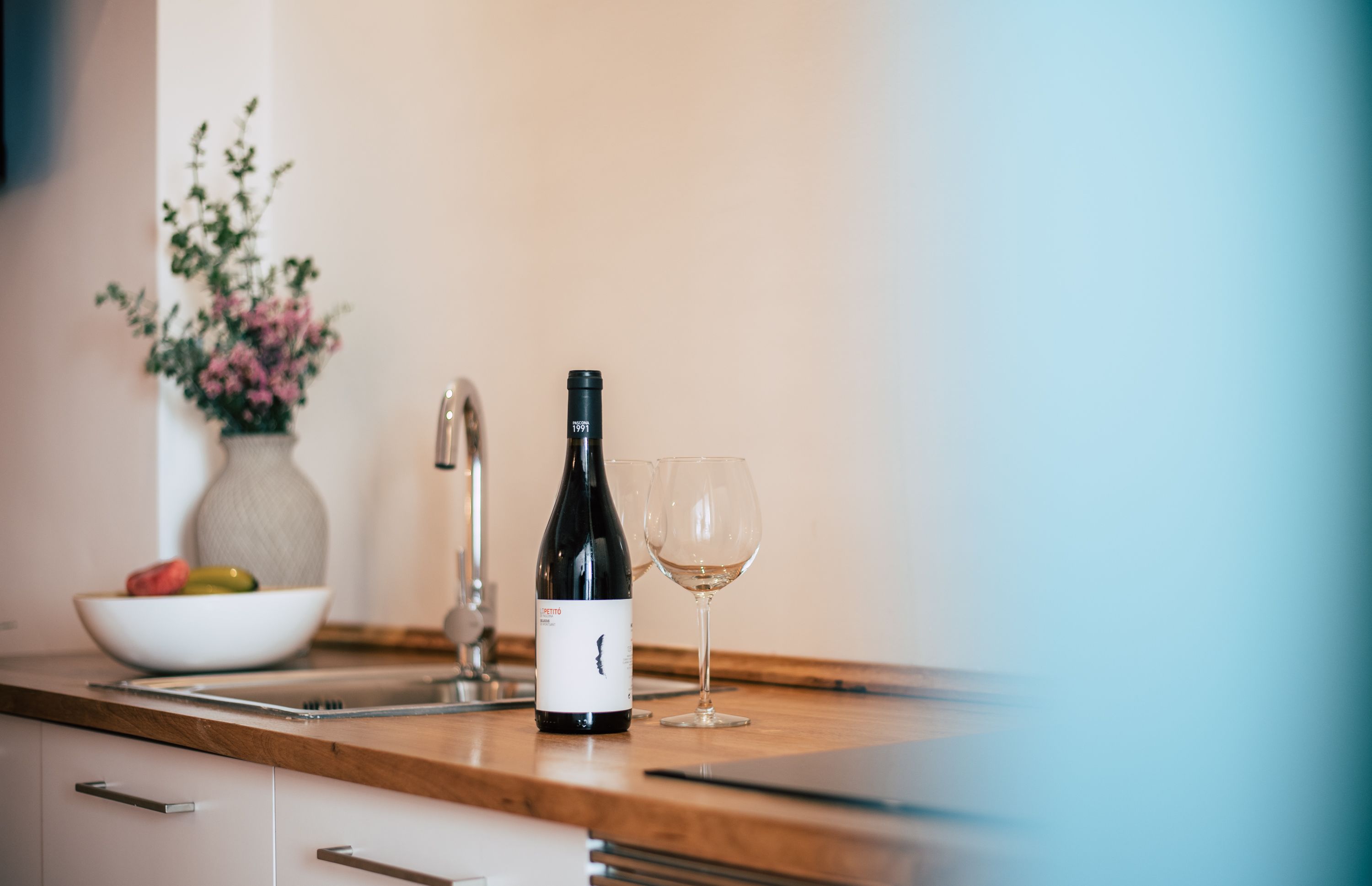 Una encimera de cocina con una botella de vino y una copa.
