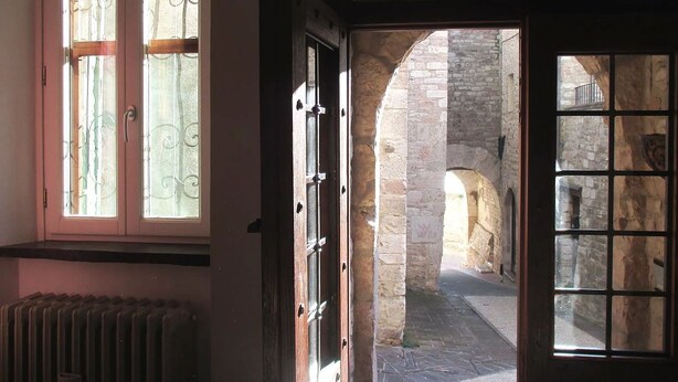 An open door leading to a stone courtyard with an archway. - Vico Del Poeta (Assisi)