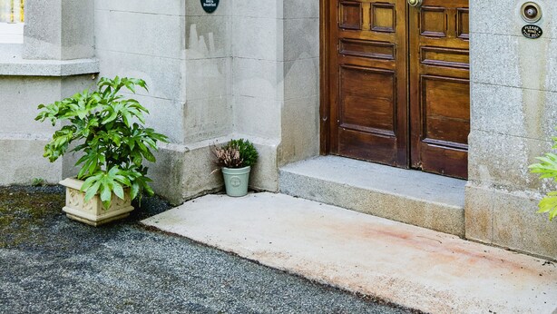 A stone building with a large wooden door, a small potted plant, and a sign on the wall. - Kiltariff Hall Country House (Newry)