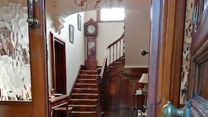 A grand staircase leading to a second floor, a large wooden door, and a chandelier. - Kiltariff Hall Country House (Newry)