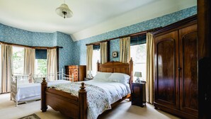 A bedroom with a wooden bed, a nightstand, a wardrobe, and a window with curtains. - Kiltariff Hall Country House (Newry)