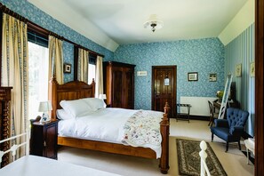 Une chambre à coucher avec un lit en bois, une chaise, un radiateur et une fenêtre avec des rideaux.
