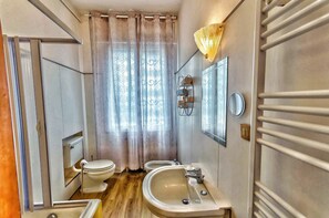 Un baño pequeño con inodoro, bidé y lavamanos.