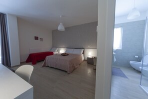A modern hotel room with a large bed, a desk, and a bathroom visible through an open door. - Ofra Matera (Matera)