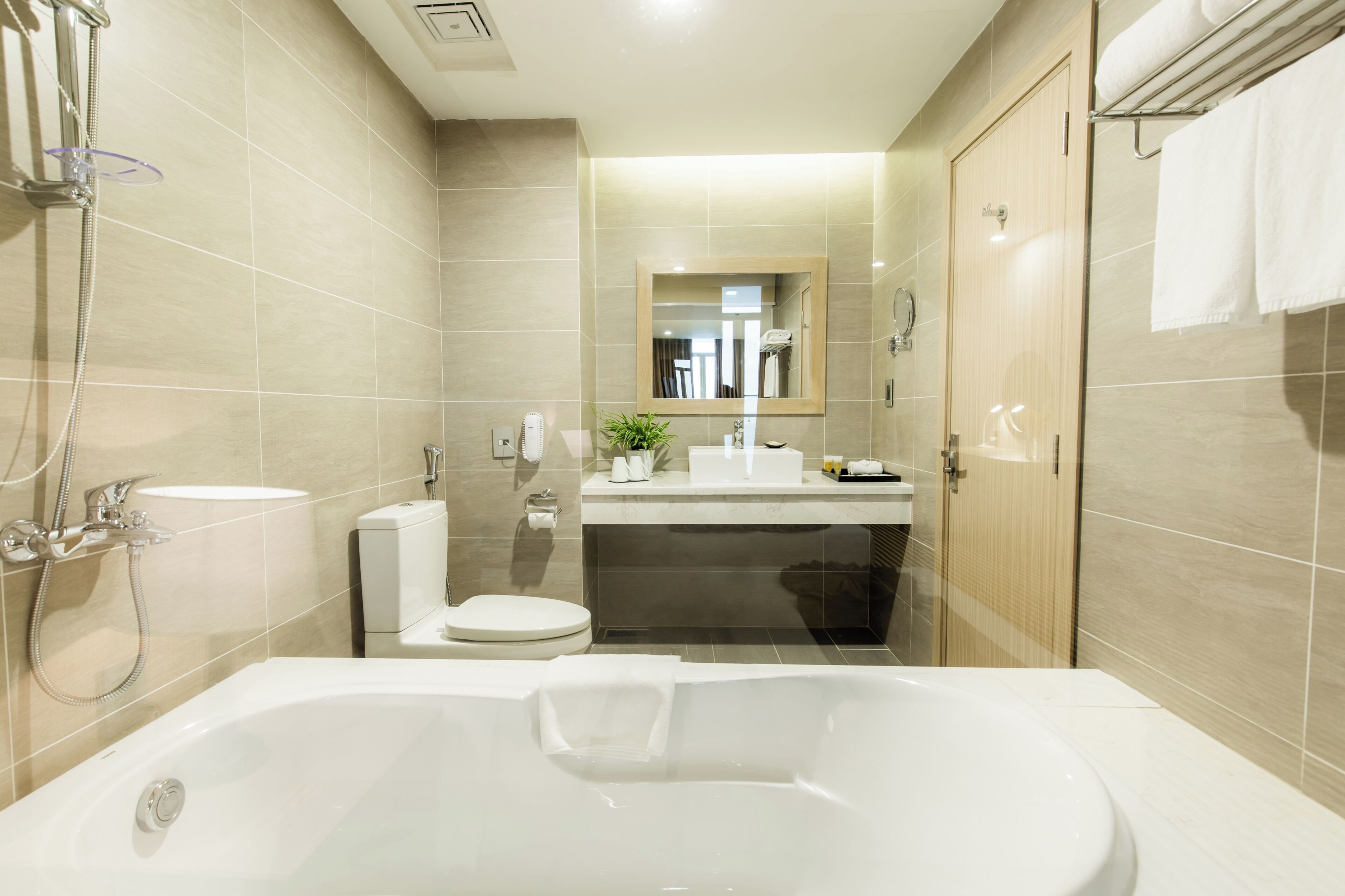 Een moderne badkamer met een bad, toilet, wastafel en douche.
