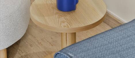 A round wooden table with a blue object on it, a white chair, and a blue couch.