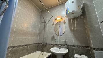 A bathroom with a bathtub, sink, and toilet. There is a towel rack and a mirror on the wall.