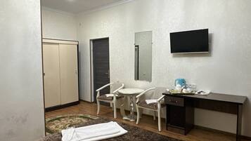 Habitación de hotel con cama, escritorio, silla, televisor y armario.