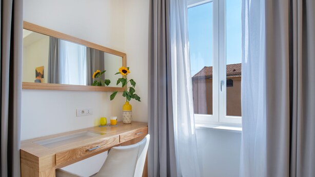 A modern bathroom with a wooden vanity, a mirror, a sink, and a window with curtains. - Corte's House (Sorrento)