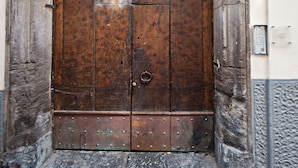A large wooden door with a metal handle, set within an arched stone frame. - Corte's House (Sorrento)