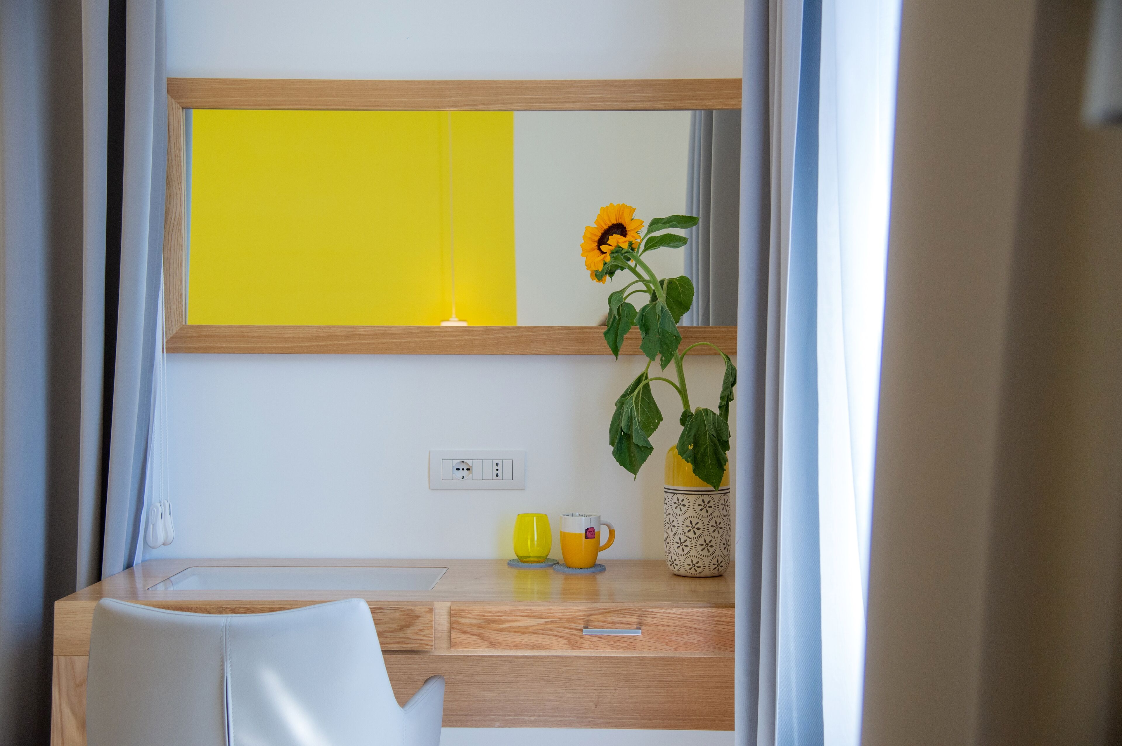Un baño moderno con tocador de madera, un espejo, una toalla amarilla y una planta en maceta.