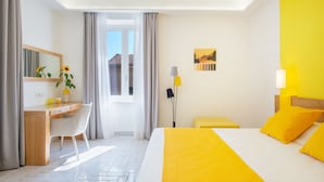 A hotel room with a bed, a desk, a chair, a lamp, and a window with curtains. - Corte's House (Sorrento)