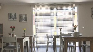 A dining area with a large window, striped curtains, and a tiled floor. - B&B Geolja (Gioia Tauro)