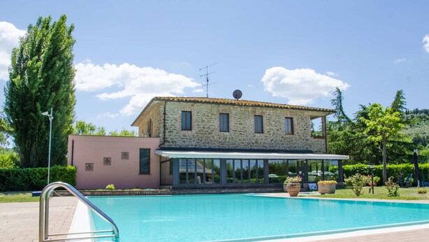 A two-story stone building with a swimming pool in front. - Hotel Villalago (Magione)