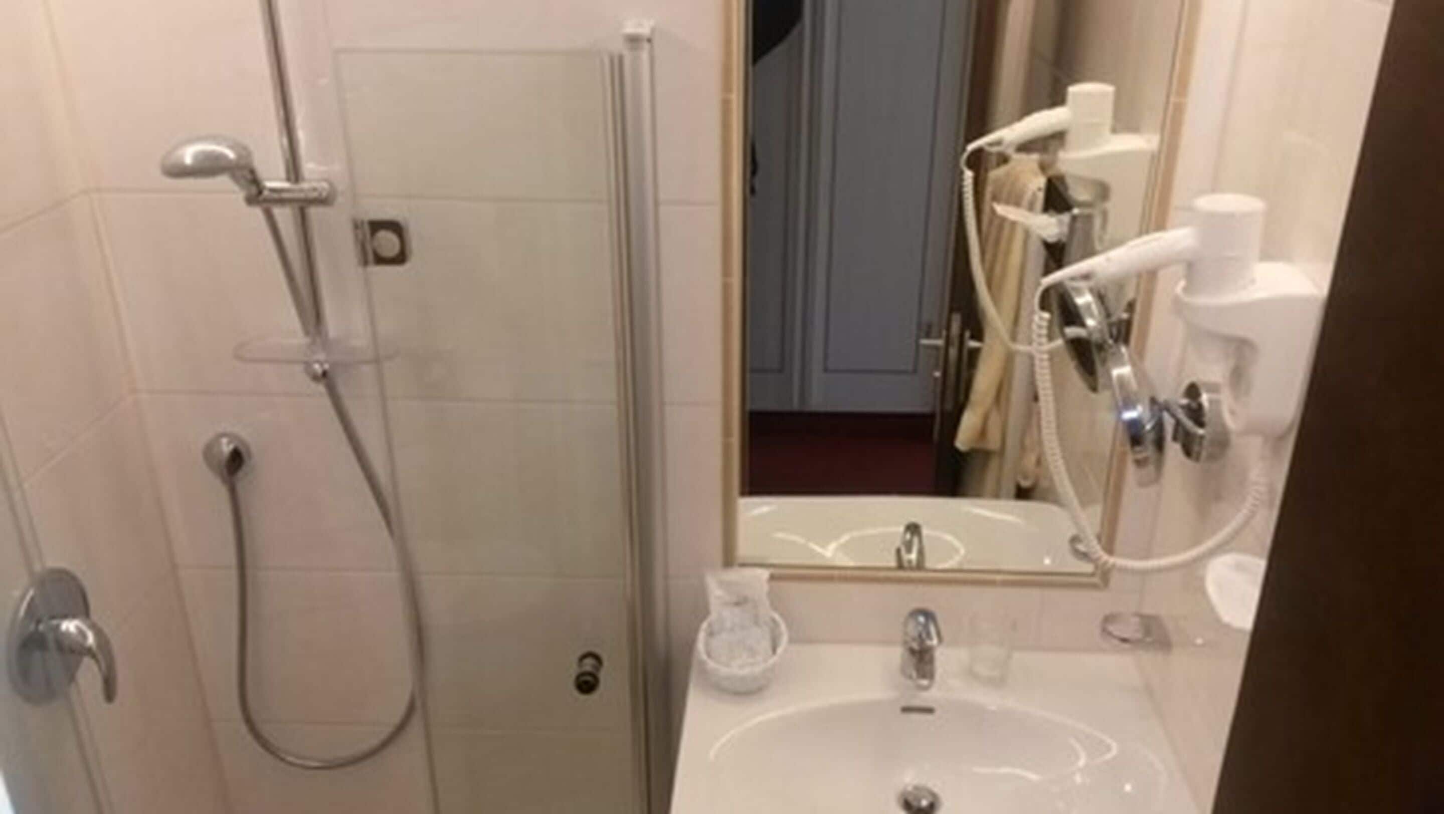 Un baño con ducha, lavabo y espejo.