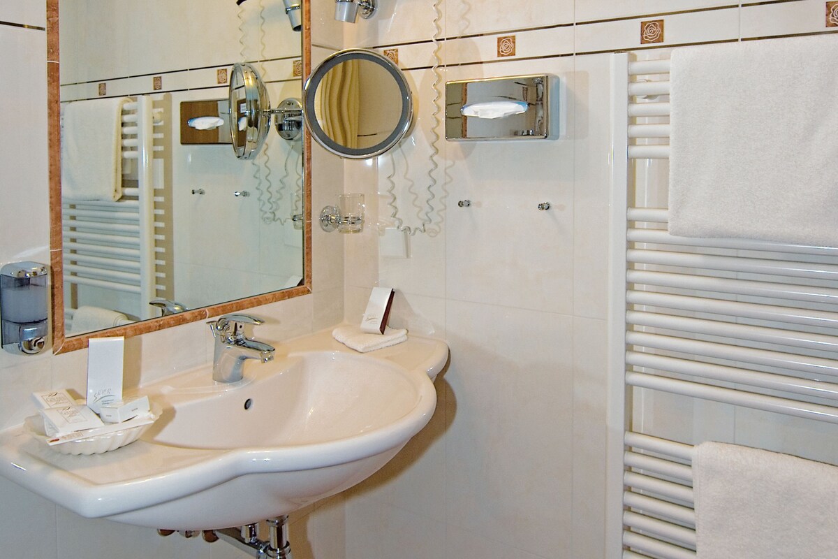 A bathroom with a sink, mirror, towel rack, and a towel hanging on the rack.