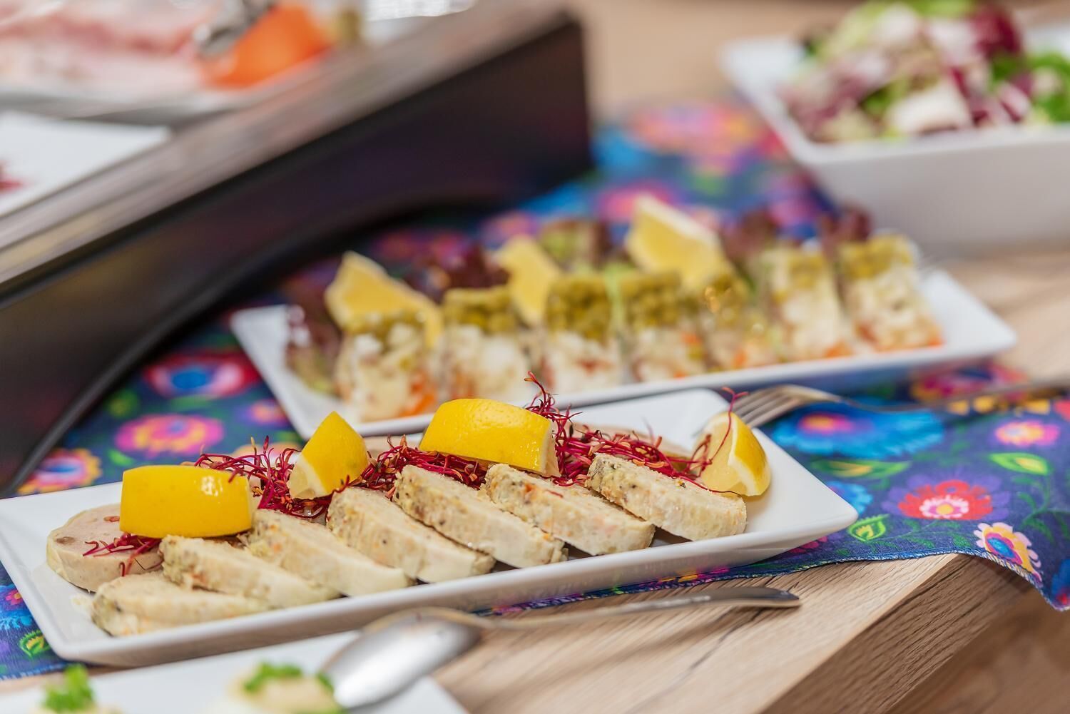 En buffet med forskellige retter, heriblandt en tallerken med skivet kød og pynt.