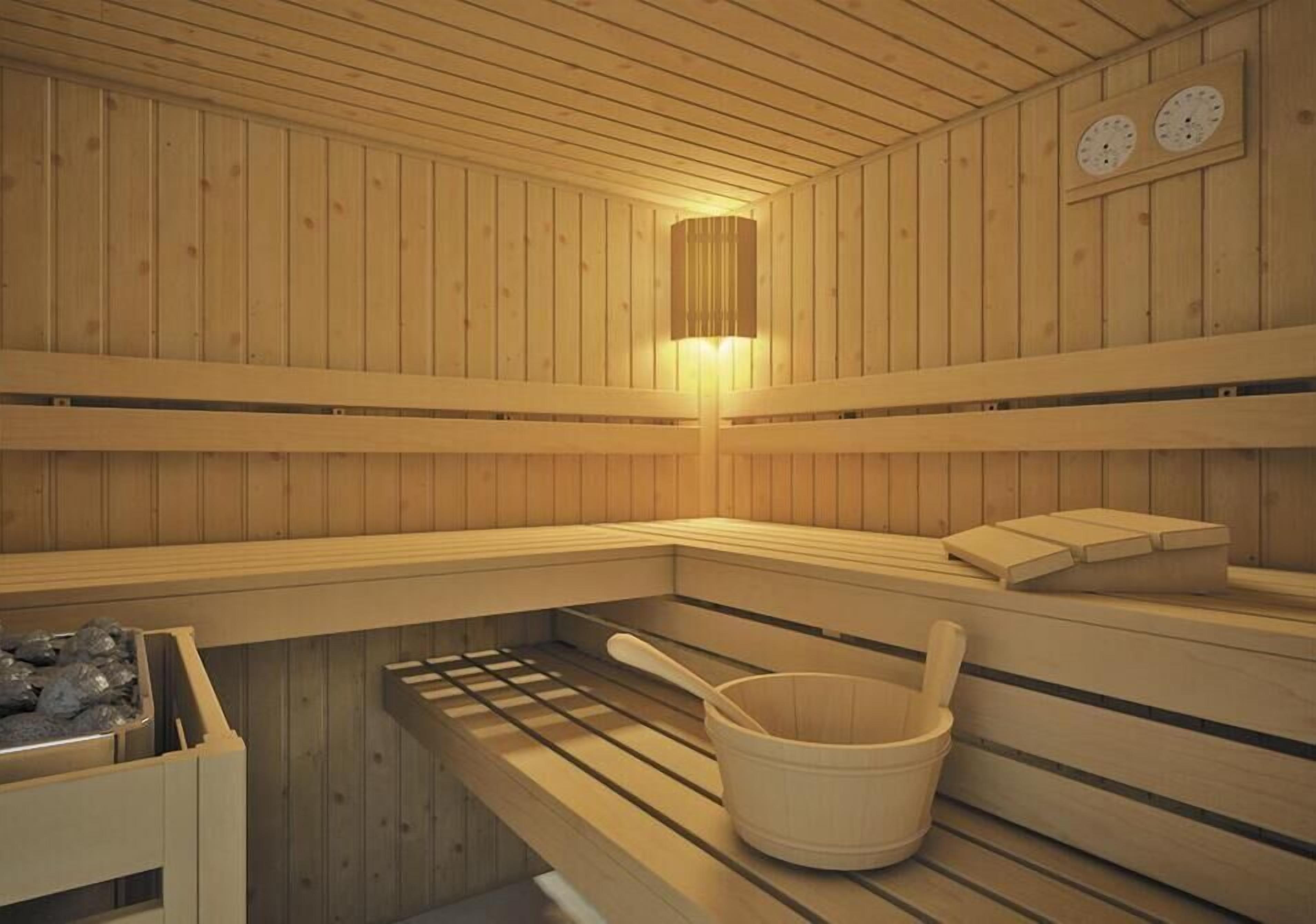 Una sauna con paredes de madera, un banco, un balde y un calentador.